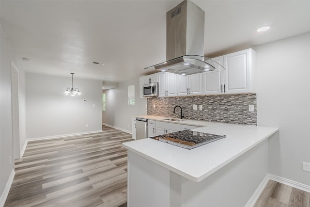 kitchen featuring island range hood, stainless steel appliances, decorative light fixtures, white cabinetry, and light wood-type flooring