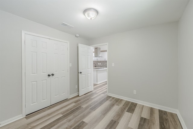 unfurnished bedroom featuring a closet, light wood-type flooring, and sink