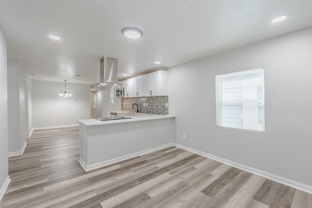 kitchen with kitchen peninsula, white cabinetry, exhaust hood, and tasteful backsplash