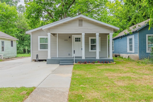 bungalow-style home with a front yard and covered porch