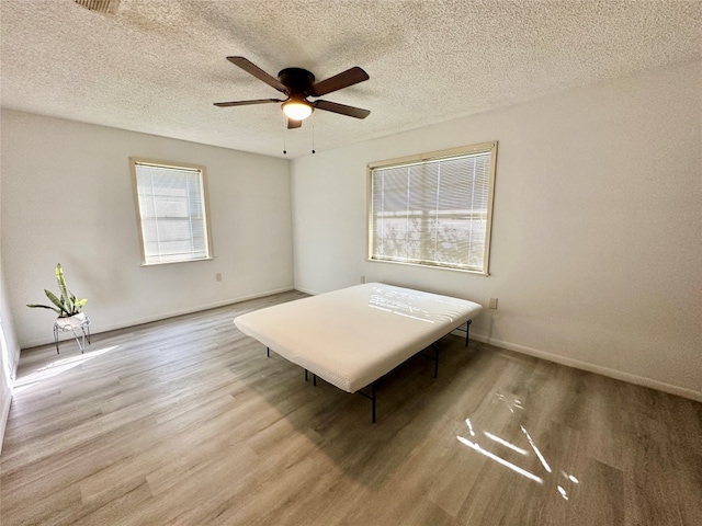 unfurnished bedroom with ceiling fan, a textured ceiling, and light hardwood / wood-style floors