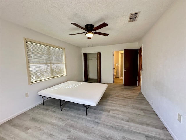 bedroom featuring ceiling fan, light wood-type flooring, and a textured ceiling