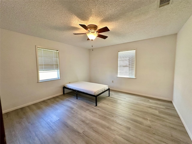 unfurnished bedroom with a textured ceiling, light hardwood / wood-style floors, and ceiling fan