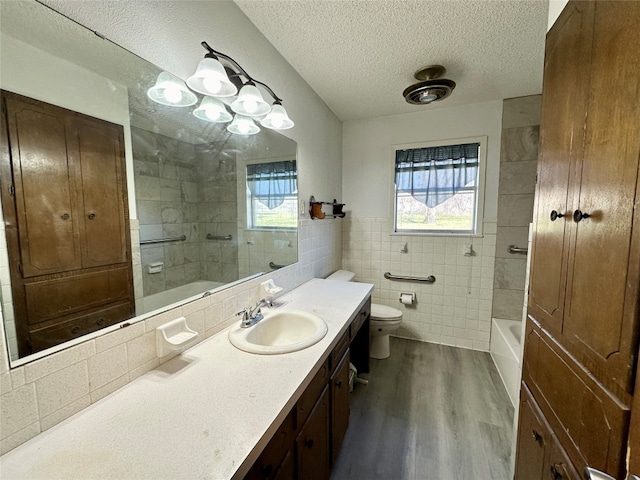 full bathroom with toilet, hardwood / wood-style floors, a textured ceiling, tile walls, and large vanity