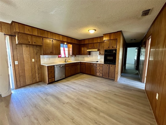 kitchen with wood walls, black appliances, and light hardwood / wood-style flooring