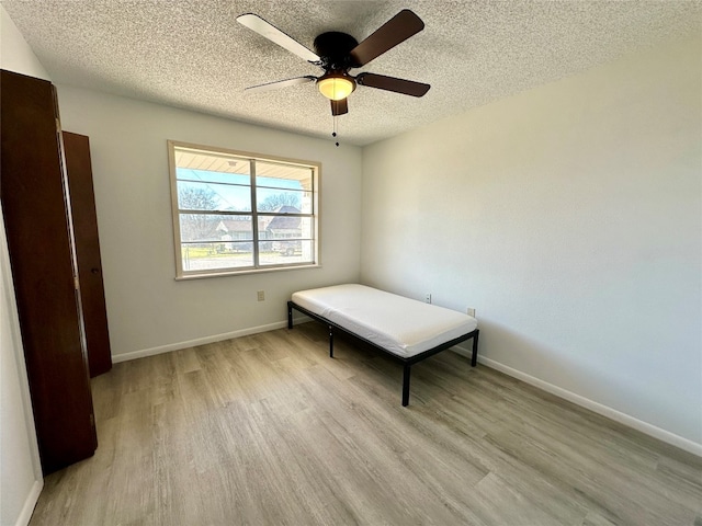 unfurnished room with ceiling fan, a textured ceiling, and light wood-type flooring