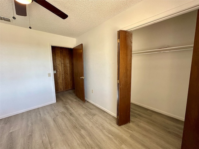 unfurnished bedroom featuring ceiling fan, a textured ceiling, light hardwood / wood-style floors, and a closet