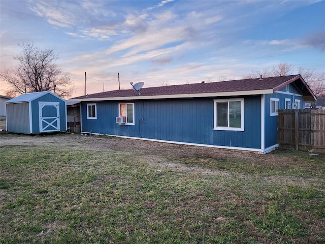 back house at dusk featuring a yard, cooling unit, and a storage shed