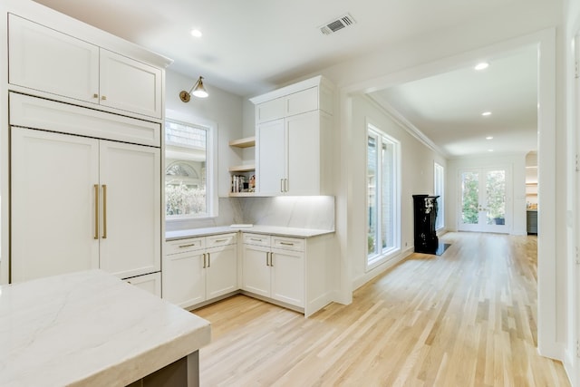 kitchen featuring tasteful backsplash, white cabinets, light wood-type flooring, and paneled built in refrigerator