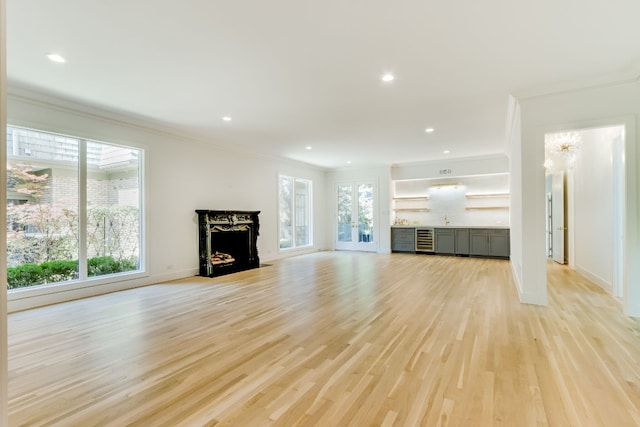 unfurnished living room featuring ornamental molding, wine cooler, and light hardwood / wood-style floors