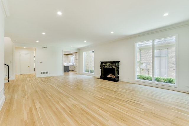 unfurnished living room with ornamental molding and light wood-type flooring