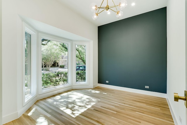 spare room featuring an inviting chandelier and light hardwood / wood-style floors