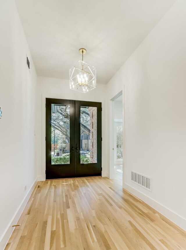 interior space with an inviting chandelier, french doors, and light hardwood / wood-style flooring