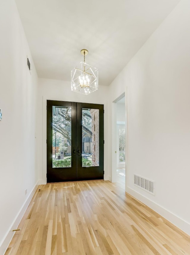 doorway featuring hardwood / wood-style floors, an inviting chandelier, and french doors