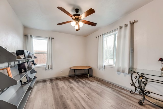 exercise area with ceiling fan and light wood-type flooring