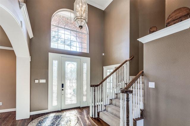 entryway featuring a chandelier, a high ceiling, crown molding, and dark wood-type flooring