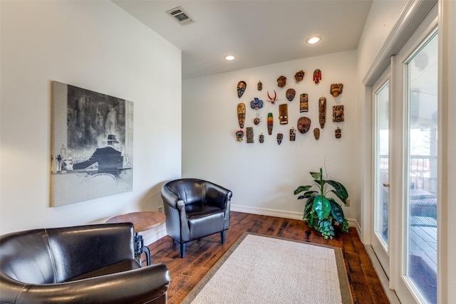 sitting room with plenty of natural light and dark wood-type flooring