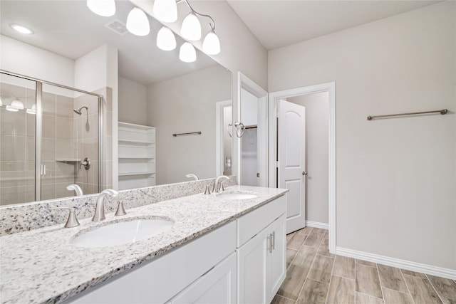 bathroom with an enclosed shower, dual sinks, and vanity with extensive cabinet space