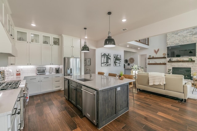 kitchen featuring sink, a center island with sink, a stone fireplace, and stainless steel appliances