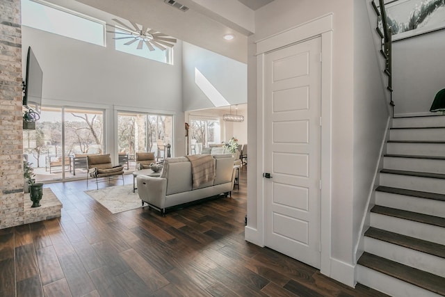 living room with dark wood-type flooring, brick wall, and a towering ceiling