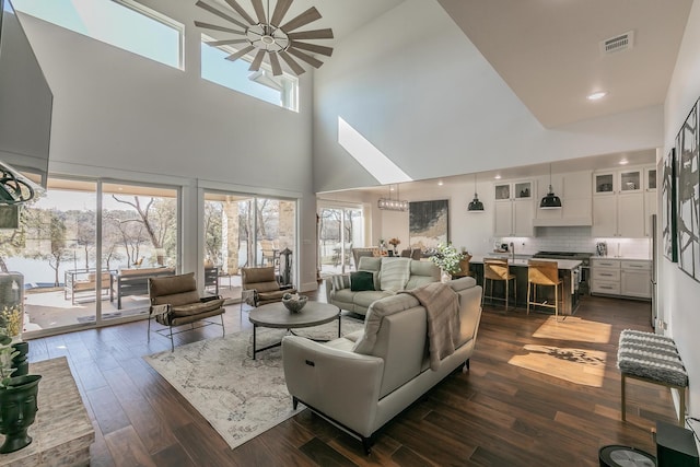 living room featuring a high ceiling, a wealth of natural light, and dark wood-type flooring