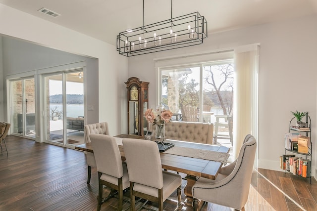 dining area featuring a water view, dark hardwood / wood-style floors, and an inviting chandelier