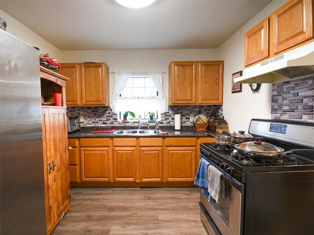 kitchen featuring appliances with stainless steel finishes, tasteful backsplash, sink, and light hardwood / wood-style flooring