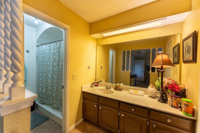 bathroom featuring tile flooring, vanity with extensive cabinet space, and a textured ceiling