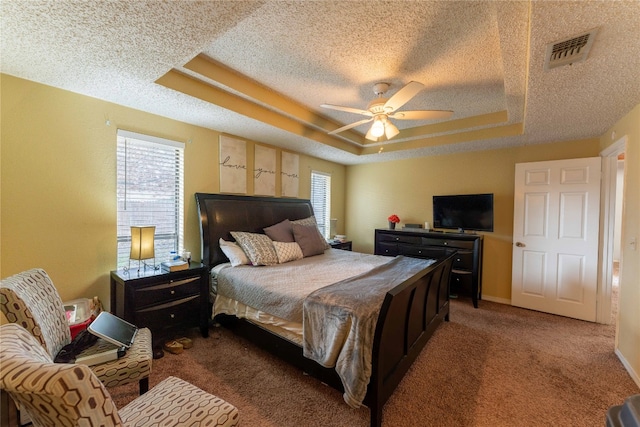 bedroom with multiple windows, carpet flooring, ceiling fan, and a tray ceiling