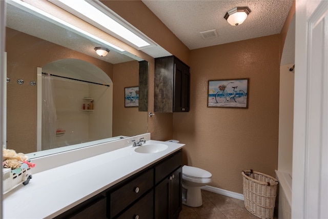 bathroom featuring a textured ceiling, toilet, tile floors, and vanity with extensive cabinet space