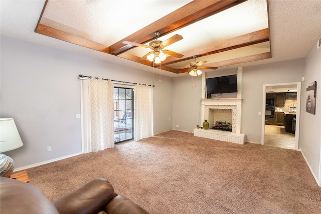 living room featuring a fireplace, a raised ceiling, ceiling fan, and light carpet