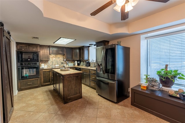 kitchen featuring backsplash, ceiling fan, light tile flooring, black appliances, and a center island