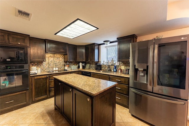 kitchen featuring a center island, light tile flooring, tasteful backsplash, black appliances, and custom range hood