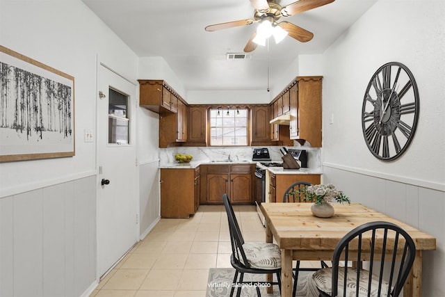 kitchen with white gas range, light tile patterned floors, backsplash, ceiling fan, and sink