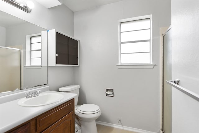 bathroom featuring a shower with door, vanity, and toilet