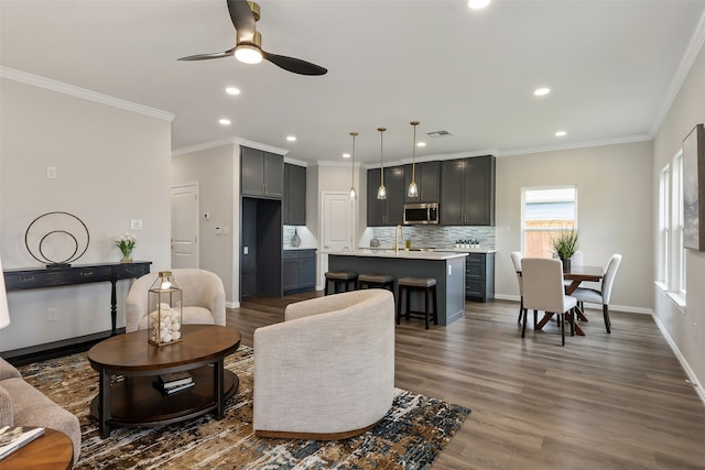 living room featuring dark hardwood / wood-style flooring, ceiling fan, and crown molding