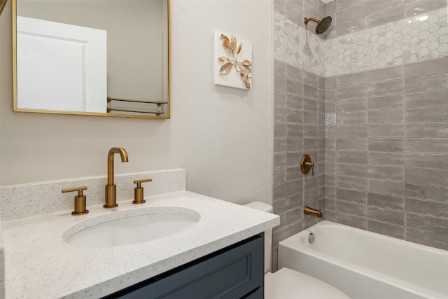 full bathroom featuring vanity, tiled shower / bath, and toilet