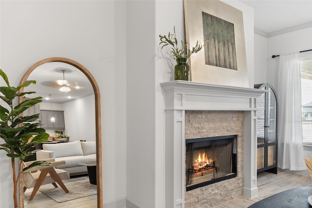 interior space featuring crown molding, a tiled fireplace, light hardwood / wood-style flooring, and ceiling fan