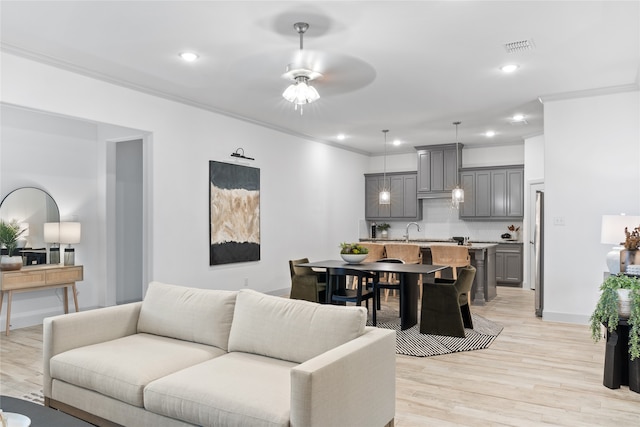 living room with ornamental molding, light wood-type flooring, and ceiling fan