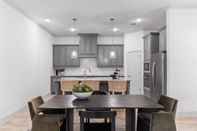 dining room featuring ornamental molding, light hardwood / wood-style floors, and sink