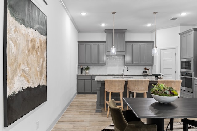 kitchen with gray cabinets, decorative light fixtures, light wood-type flooring, and tasteful backsplash