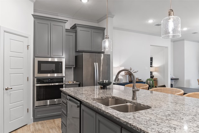 kitchen featuring ornamental molding, appliances with stainless steel finishes, sink, and light stone countertops