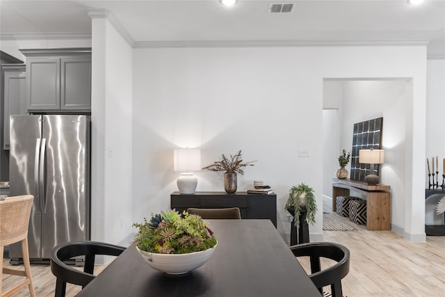 dining space with light hardwood / wood-style flooring and crown molding