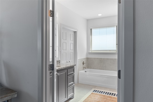 bathroom featuring vanity, tile patterned flooring, and a bath