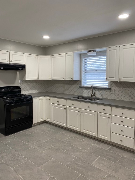 kitchen featuring exhaust hood, black gas range oven, tasteful backsplash, white cabinets, and sink