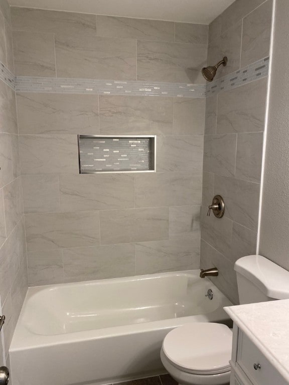 full bathroom featuring tiled shower / bath, toilet, and vanity