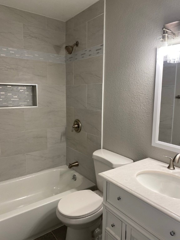 full bathroom featuring vanity, tile floors, toilet, and tiled shower / bath