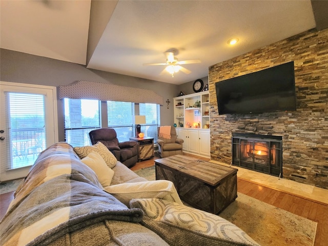 living room with a stone fireplace, hardwood / wood-style floors, and ceiling fan