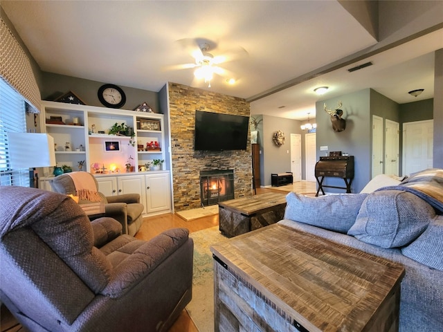 living room featuring ceiling fan with notable chandelier and a fireplace