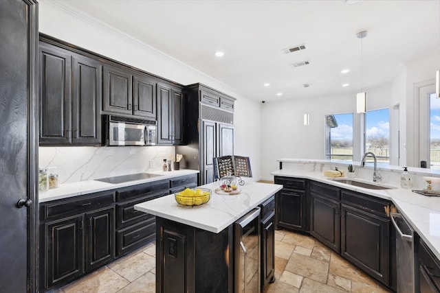 kitchen with pendant lighting, backsplash, a kitchen island, sink, and appliances with stainless steel finishes